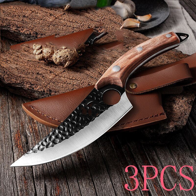 Curved butcher knife with hammered black blade and wooden handle beside brown leather sheath on rustic wood surface.