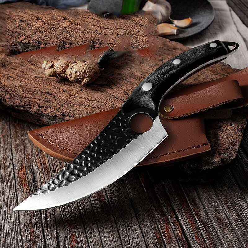 Curved black butcher knife with textured blade and ergonomic handle resting on brown leather sheath on wooden surface.