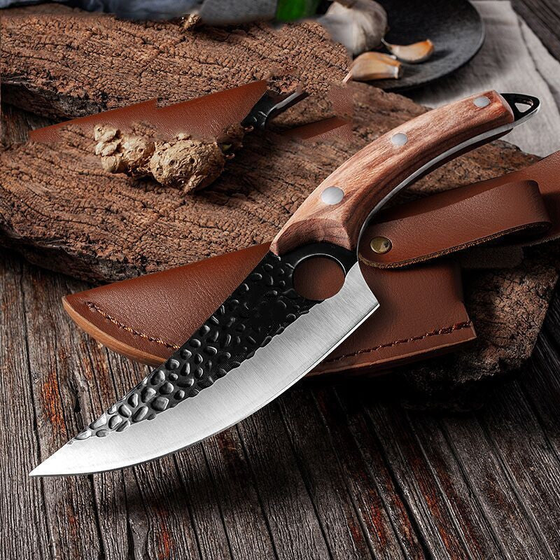 Butcher's scimitar knife with hammered blade and wood handle resting on brown leather sheath on wooden surface.