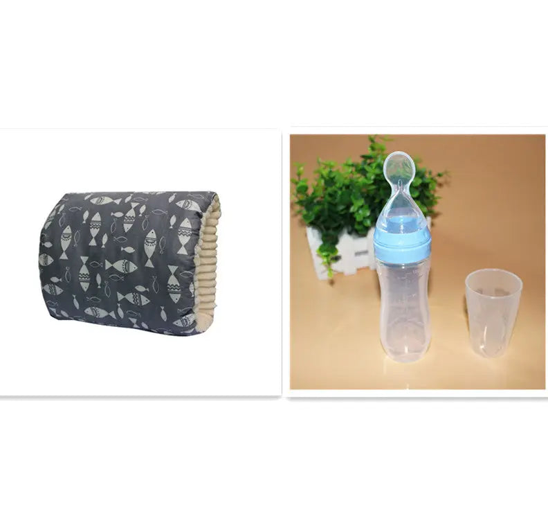 Dark blue nursing pillow with fish pattern and beige inner lining alongside a baby bottle with blue cap and a clear plastic.
