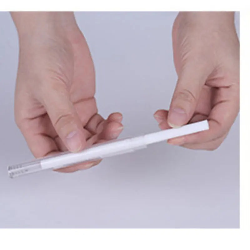 Hands holding a white USB air humidifier with a slim cylindrical design and transparent tip.