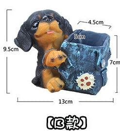 Small black and brown puppy figurine holding a blue textured container with paw print detail.