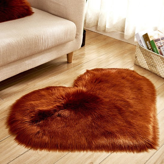 Fluffy heart-shaped plush carpet in claret red on wooden floor by beige sofa.