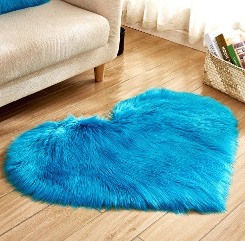 Fluffy heart-shaped blue plush rug with non-slip backing on wooden floor next to beige sofa.