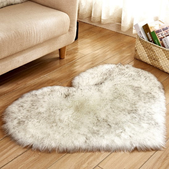 Fluffy heart-shaped plush carpet in soft gray with a non-slip backing on hardwood floor.