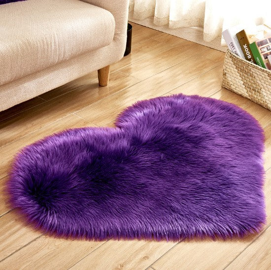 Large fluffy heart-shaped rug in vibrant violet with soft plush texture on wooden floor.